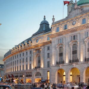 Stunning exterior of Hotel Cafe Royal London, showcasing neoclassical architecture, grand arches, and ambient evening lighting, offering a deluxe experience with Natlaupa.