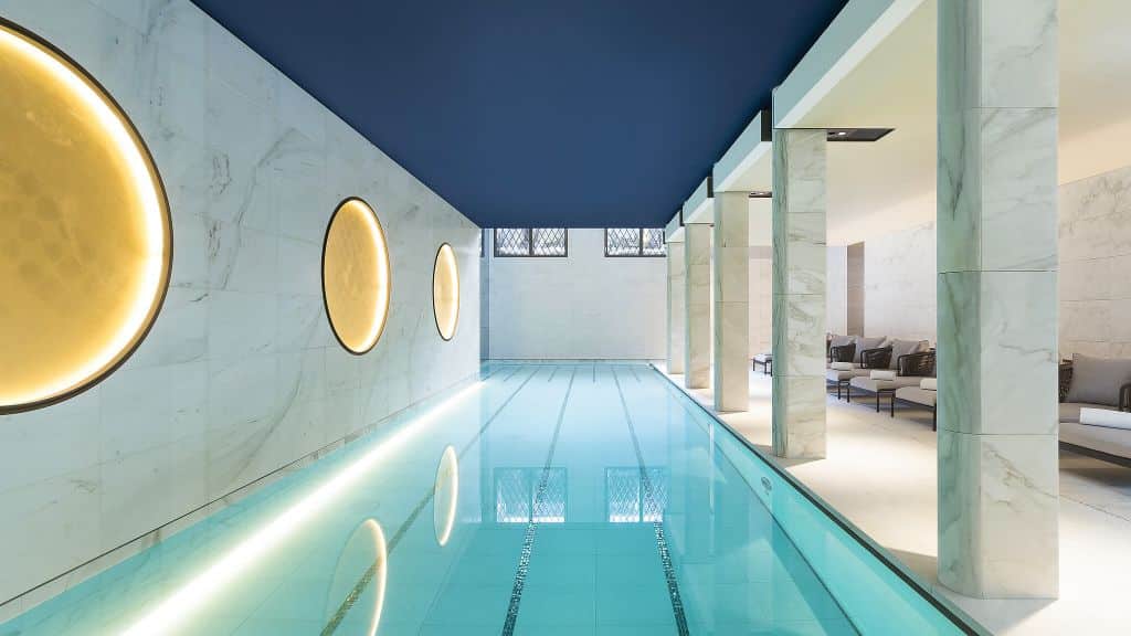 Luxurious indoor swimming pool with marble columns, elegant lighting, and modern design, offering a serene retreat with Natlaupa.