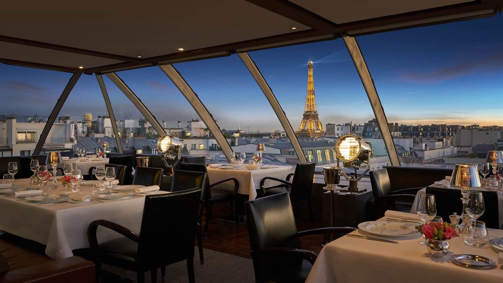 Luxurious rooftop terrace dining area in Paris with an unobstructed view of the Eiffel Tower, elegant seating, and soft ambient lighting, offering a refined experience with Natlaupa.