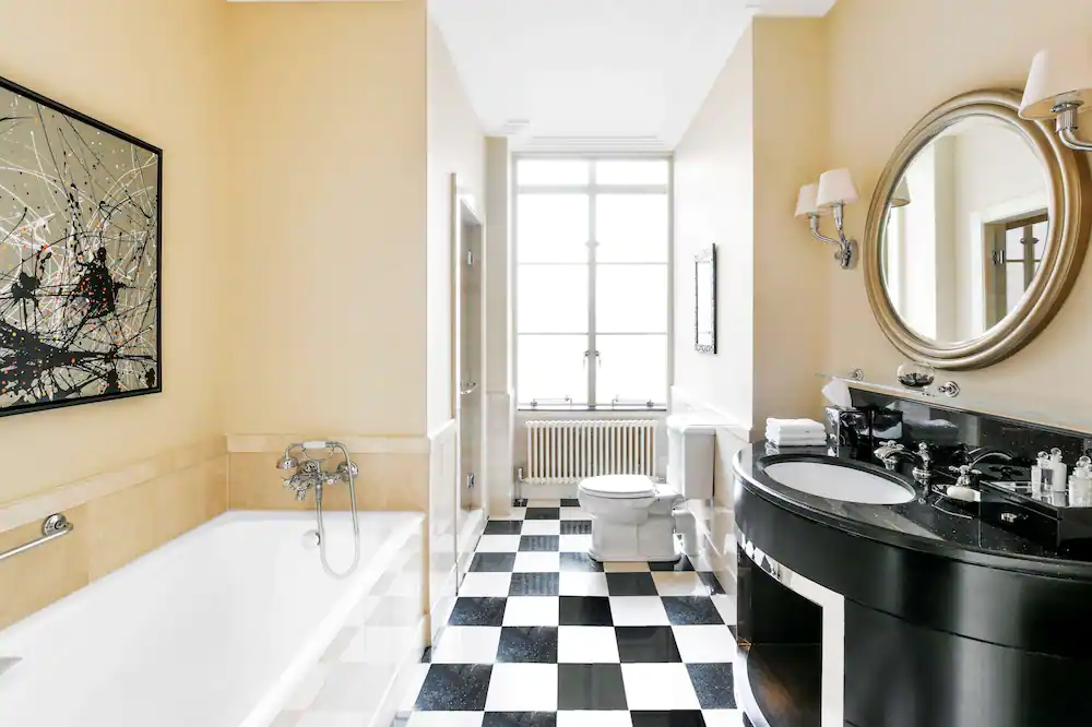 Elegant bathroom with a luxurious bathtub, black vanity, and checkered flooring, blending classic and contemporary design with Natlaupa.