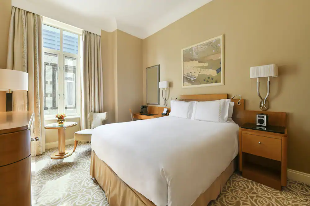 Cozy and elegant hotel room with a plush bed, inviting seating area, soft lighting, and minimalist décor, offering a serene retreat with Natlaupa.